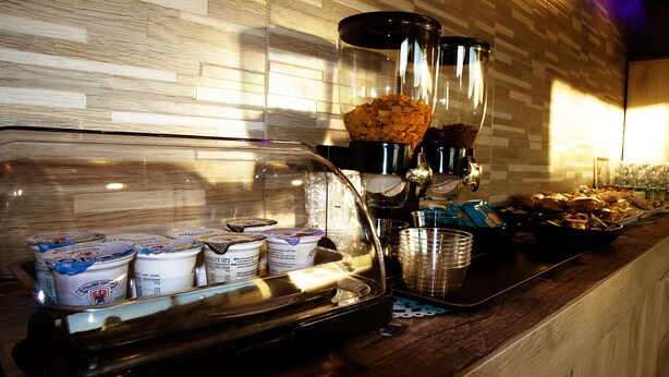 Uma estação de café com máquina de café, chávenas e uma taça de cereais.