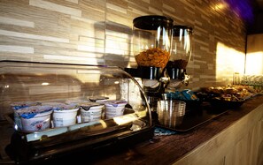 Un angolo caffè con una macchina da caffè, tazze e una ciotola di cereali.