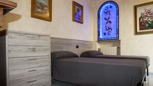 Quarto com uma cama, penteadeira de madeira e vitral.