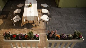 Uma área de refeições com mesa e cadeiras, dois vasos de flores e um padrão de piso em herringbone.