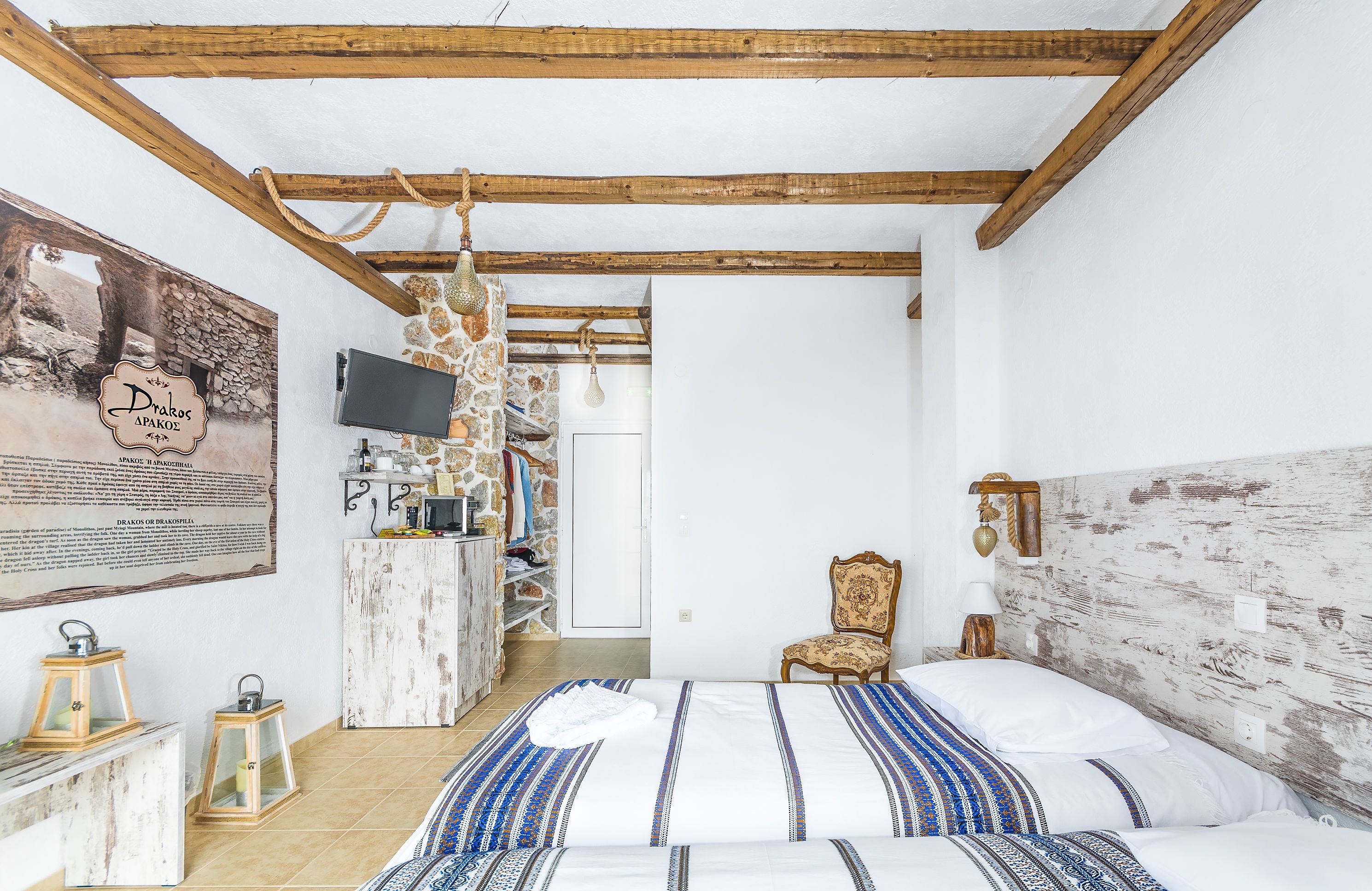 A bedroom with a bed, a chair, a TV, and a stone wall.