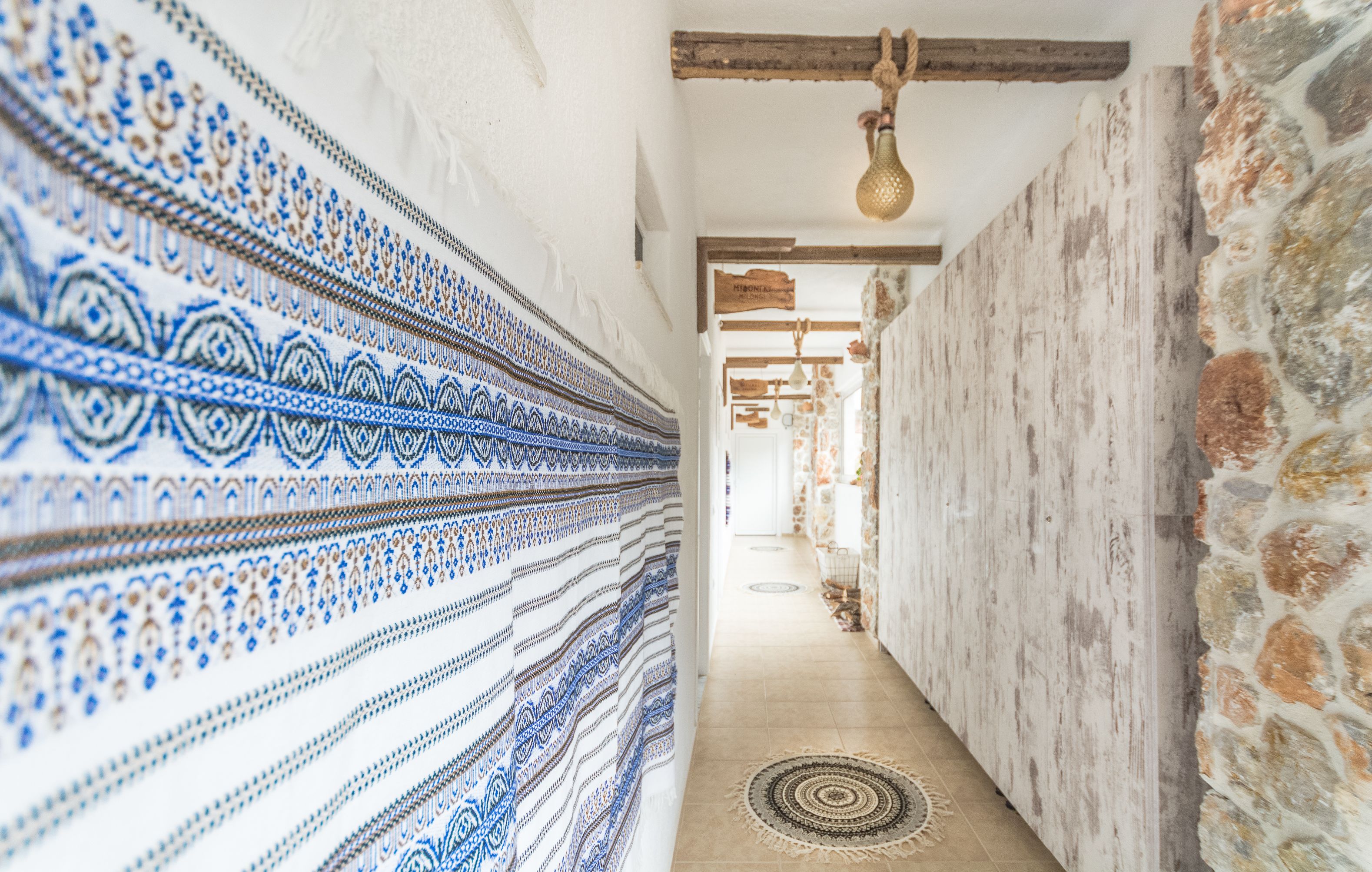 Ein Korridor mit einem Wandteil, der mit gemustertem Stoff verziert ist, einem Mauerwerk an der gegenüberliegenden Wand und einem Holzbalken an der Decke.
