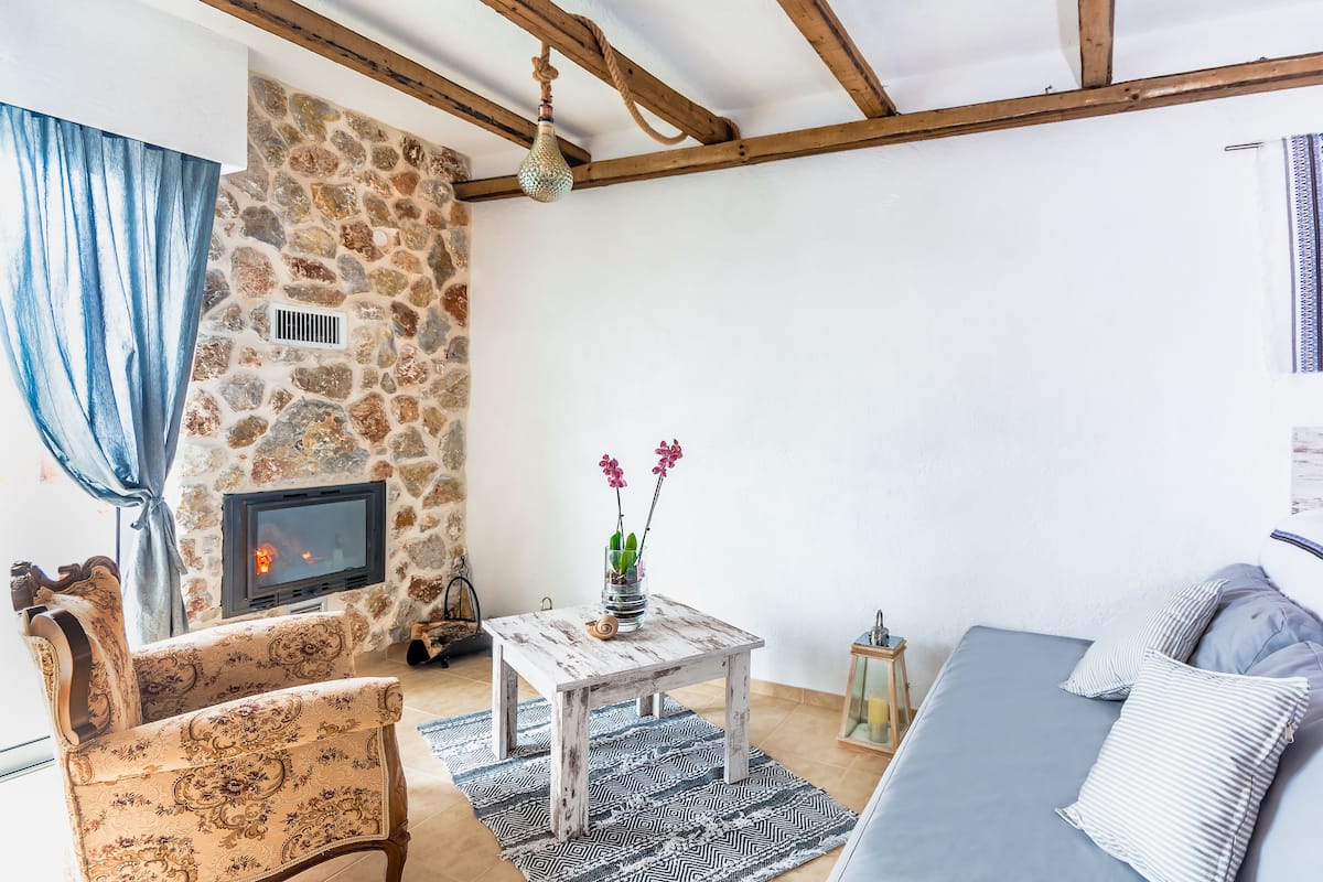 Ein gemütliches Wohnzimmer mit Steinwand, Kamin, einer Couch und einem gemusterten Teppich.