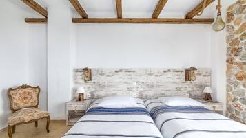 Un dormitorio con una cabecera de madera rústica, dos mesitas de noche con lámparas, una silla y una cama con ropa de cama a rayas.