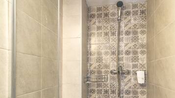 A shower with a glass door, tiled walls with a patterned design, and a showerhead.
