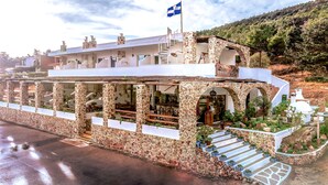 A stone building with a flag, outdoor seating, and a staircase leading to the entrance. - Limeri Traditional Guest House (Rhodes)