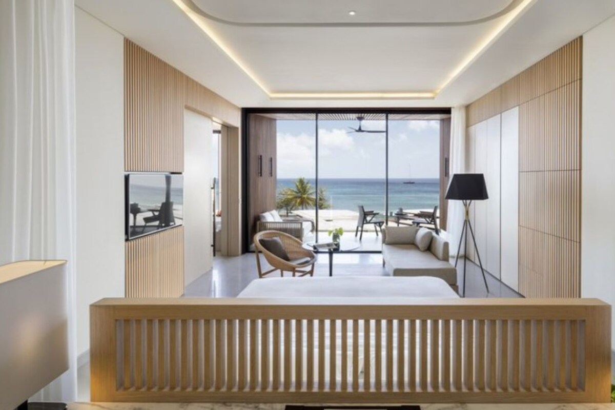Une chambre d’hôtel moderne dotée d’une grande fenêtre, d’un canapé, d’une table à manger et d’une lampe.