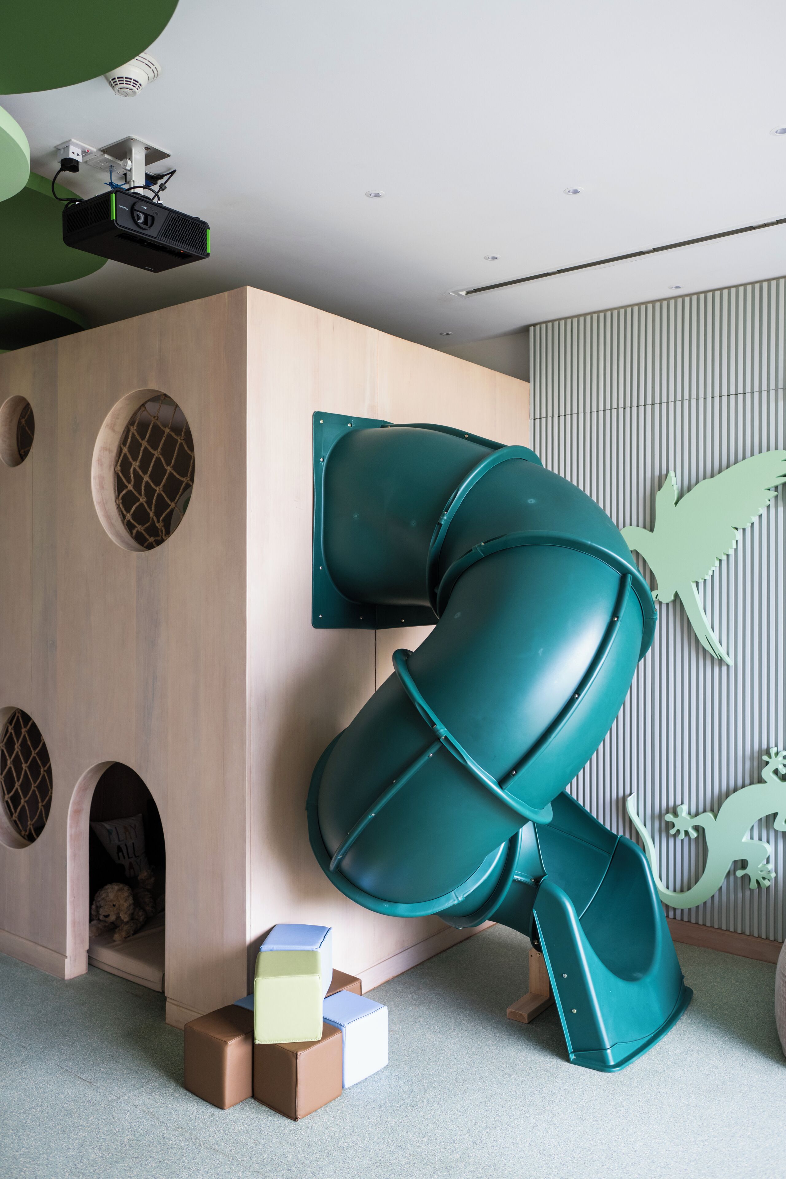 A play area with a slide, a wooden playhouse, and a wall with animal silhouettes.