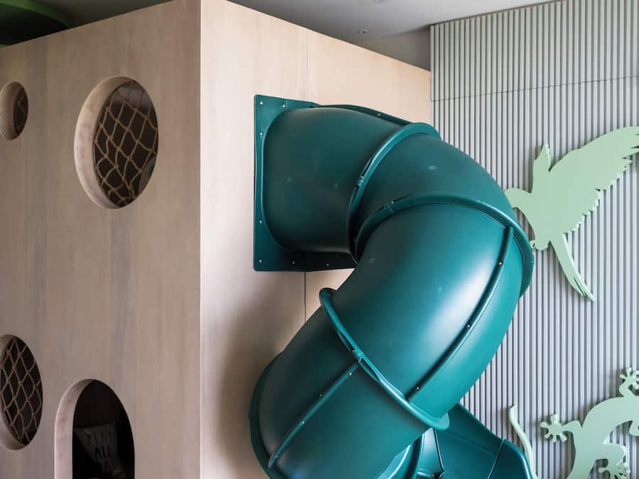 A play area with a slide, a wooden playhouse, and a wall with animal silhouettes.