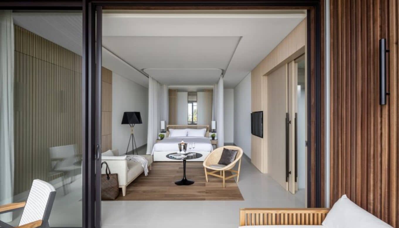 A modern hotel room with a bed, a small table, a chair, and a TV.