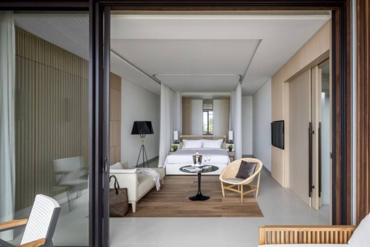 A modern hotel room with a bed, a small table, a chair, and a TV.