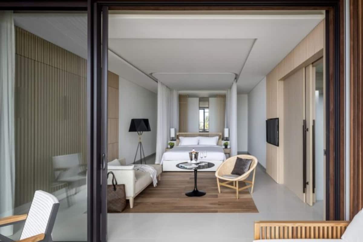 A modern hotel room with a bed, a small table, a chair, and a TV.