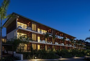 A multi-story hotel with balconies, wooden paneling, and a landscaped garden.