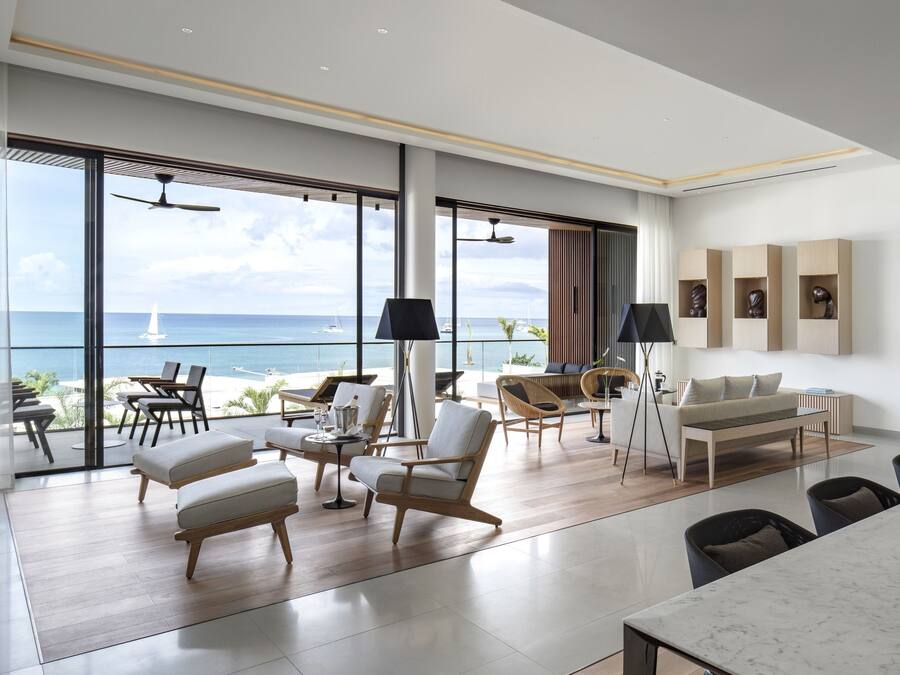 A spacious living area with a large window overlooking the sea, furnished with a sofa, chairs, and a dining table.