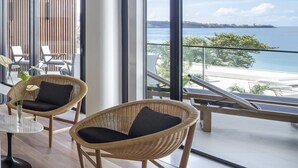 A modern room with large windows, wicker chairs, a round table, and a view of the sea. - Silversands Grand Anse (St. George's)