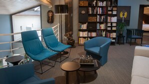 A modern living room with blue armchairs, a bookshelf, and a chessboard. - La Closerie aux Violettes chambres d'hôtes (Toulouse)