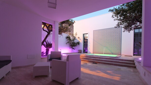 An outdoor patio area with wicker furniture, a small pool, and a decorative wall. - La Casa Del Mercante (Racale)