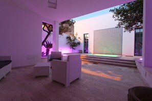 An outdoor patio area with wicker furniture, a small pool, and a decorative wall.