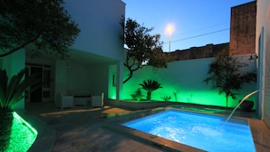 A swimming pool with a surrounding patio area, including a seating area and plants. - La Casa Del Mercante (Racale)