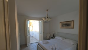 A bedroom with a bed, a chair, a nightstand, and a framed picture on the wall. - La Casa Del Mercante (Racale)