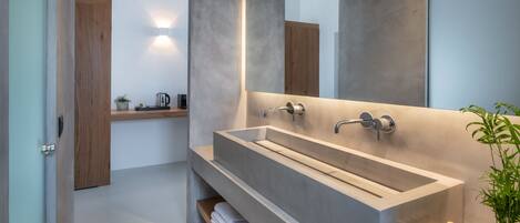 A modern bathroom with a large rectangular sink, a mirror, and a shelf with towels.