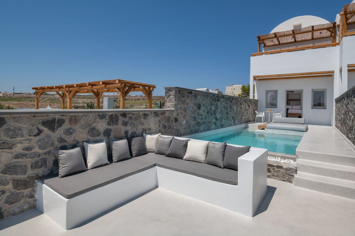 A modern outdoor seating area with a stone wall and a pool.