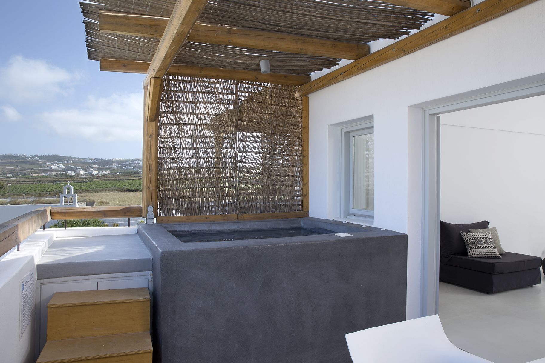A balcony with a view of the countryside, a covered seating area, and a small outdoor kitchen.