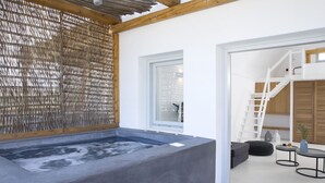 Un baño moderno con una bañera grande, techo de madera y puerta de cristal que da a una sala de estar.