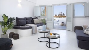 Una sala moderna con un sofá, dos mesas redondas y un balcón con vistas.
