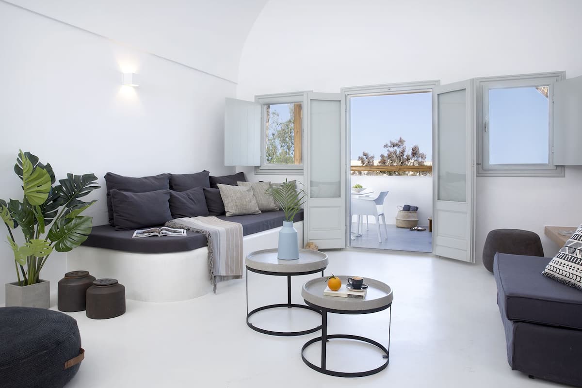 A modern living room with a sofa, two round tables, and a balcony with a view.