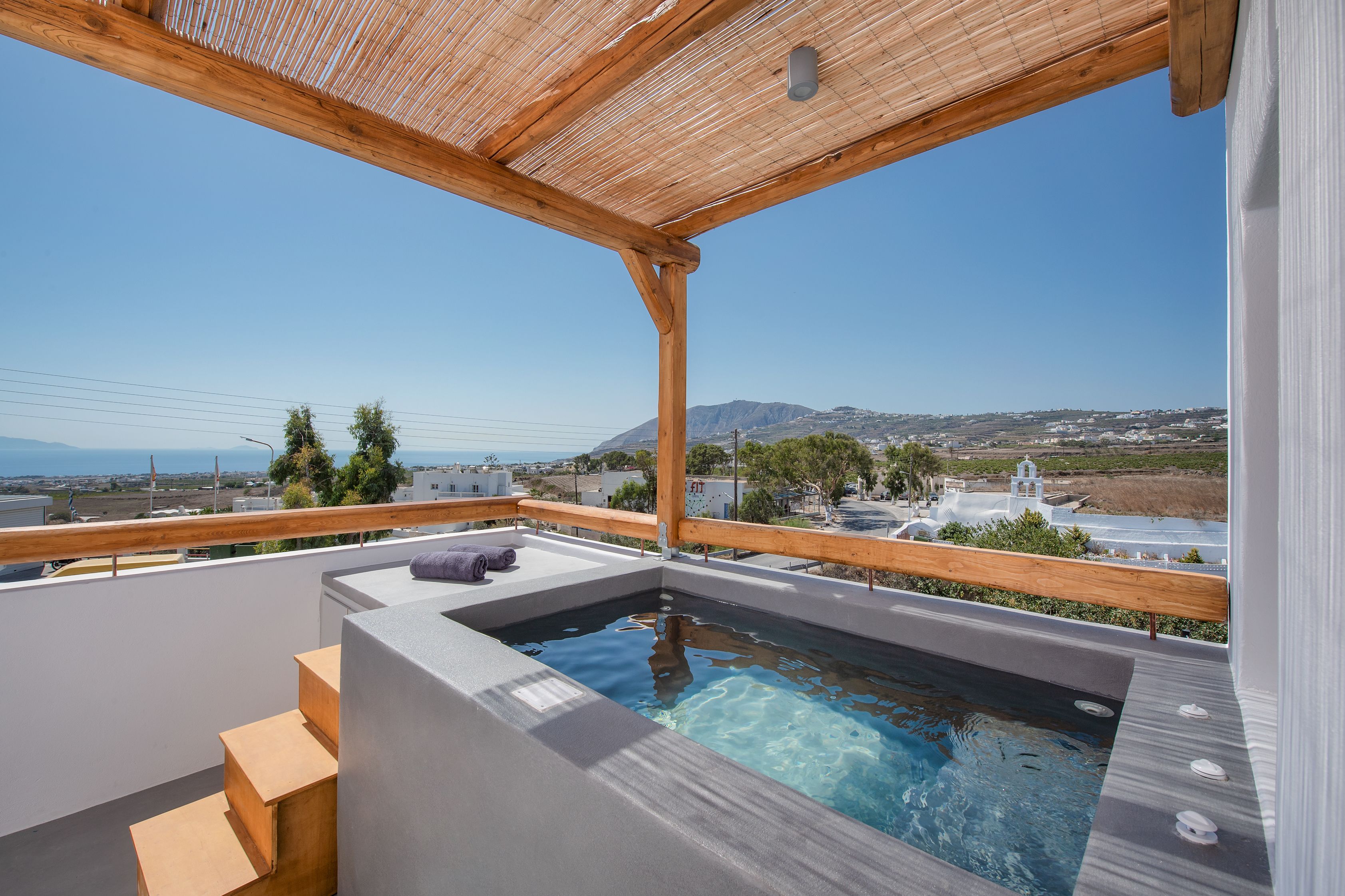 A rooftop pool with a wooden pergola, a small staircase, and a view of the landscape.