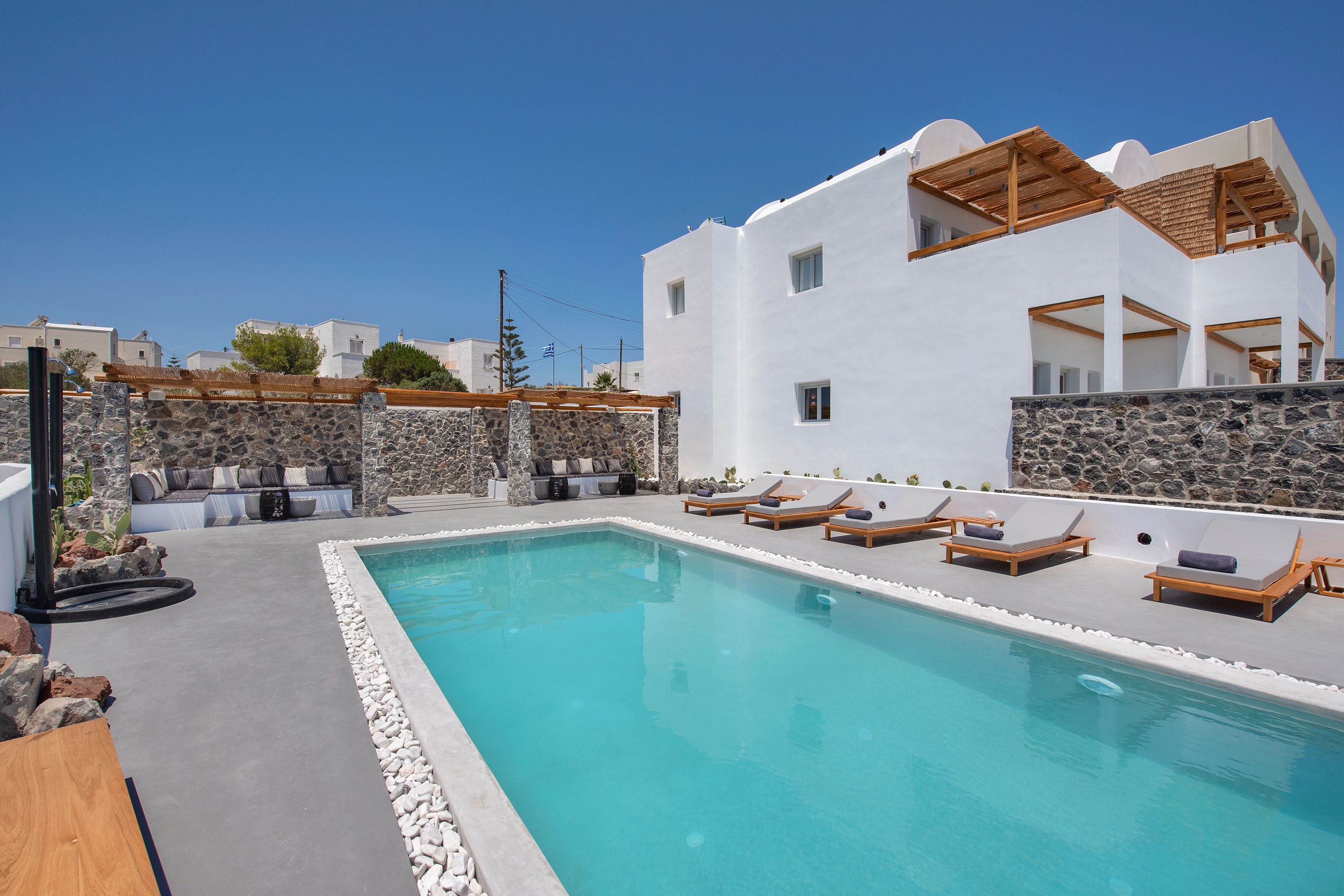 A pool area with lounge chairs and a stone wall.