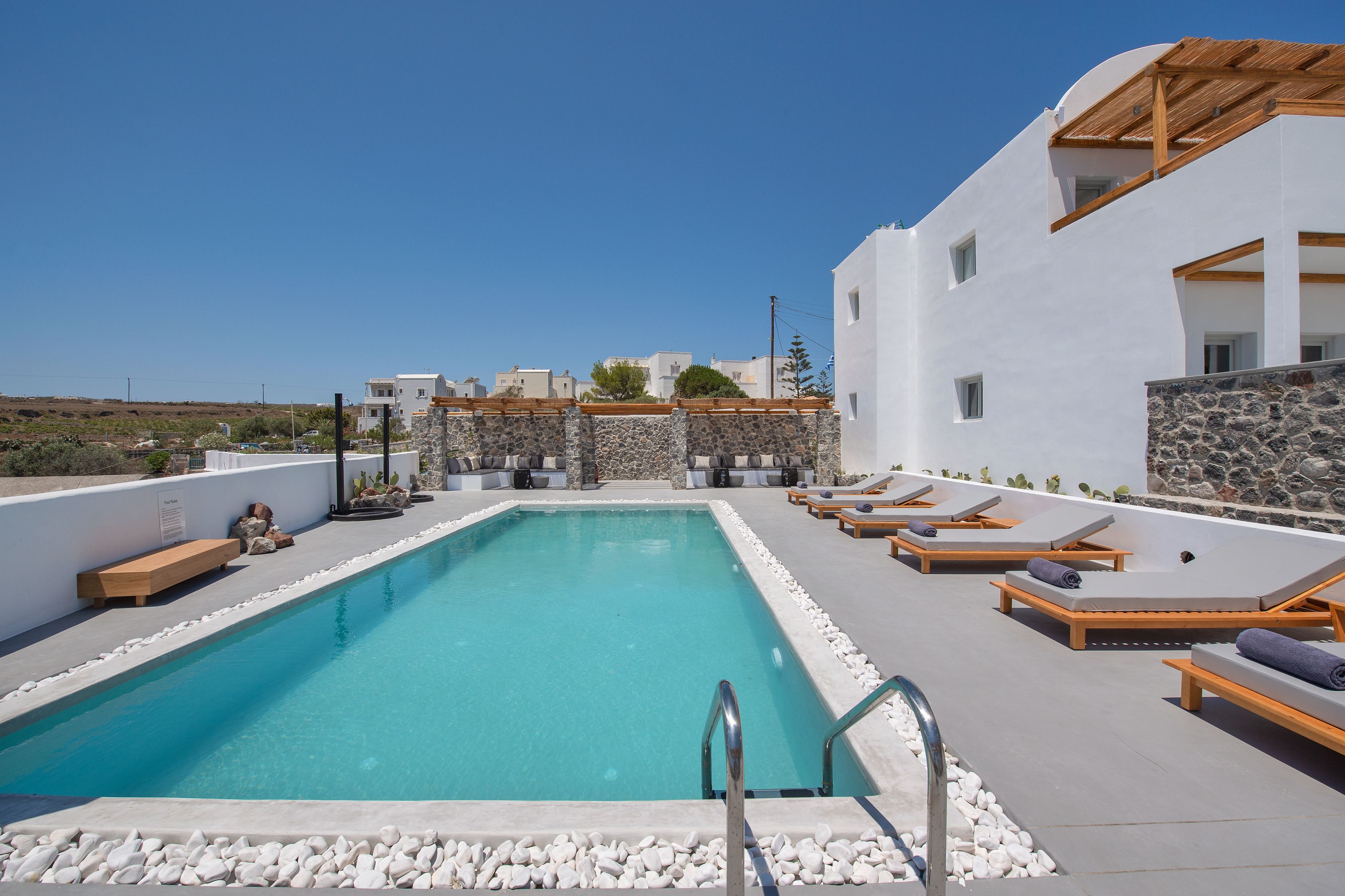 A rooftop pool with lounge chairs and a stone wall.