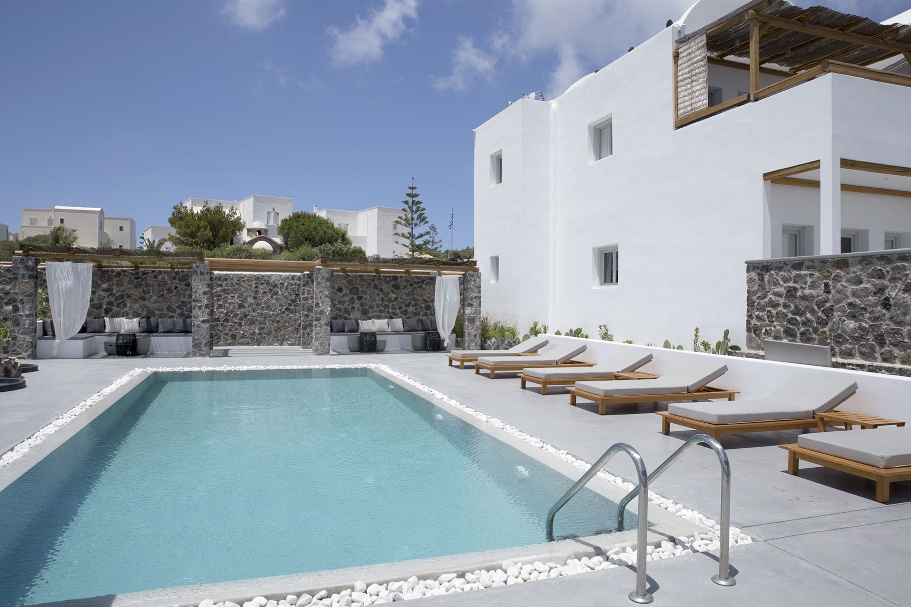 A pool area with lounge chairs and a stone wall.