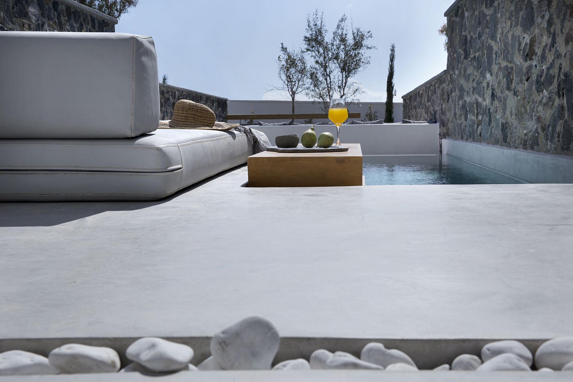 Ein moderner Außenbereich mit Sitzgelegenheit, Pool, Steinmauern und blauem Himmel.