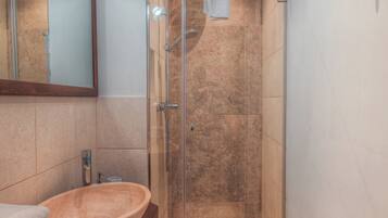 Un bagno con doccia vetrata, mobile lavabo in legno e specchio sopra il lavandino.