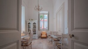 A hallway with white furniture, a cabinet, and a window with curtains. - Palazzo Vaglio Relais (Nardò)