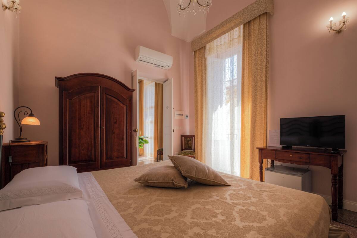 Une chambre d’hôtel avec un grand lit, une télévision, un bureau et un appareil de climatisation.