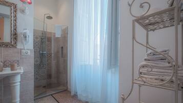 Un bagno con doccia, porta in vetro, mobile lavabo con specchio e lampada, e porta asciugamani.
