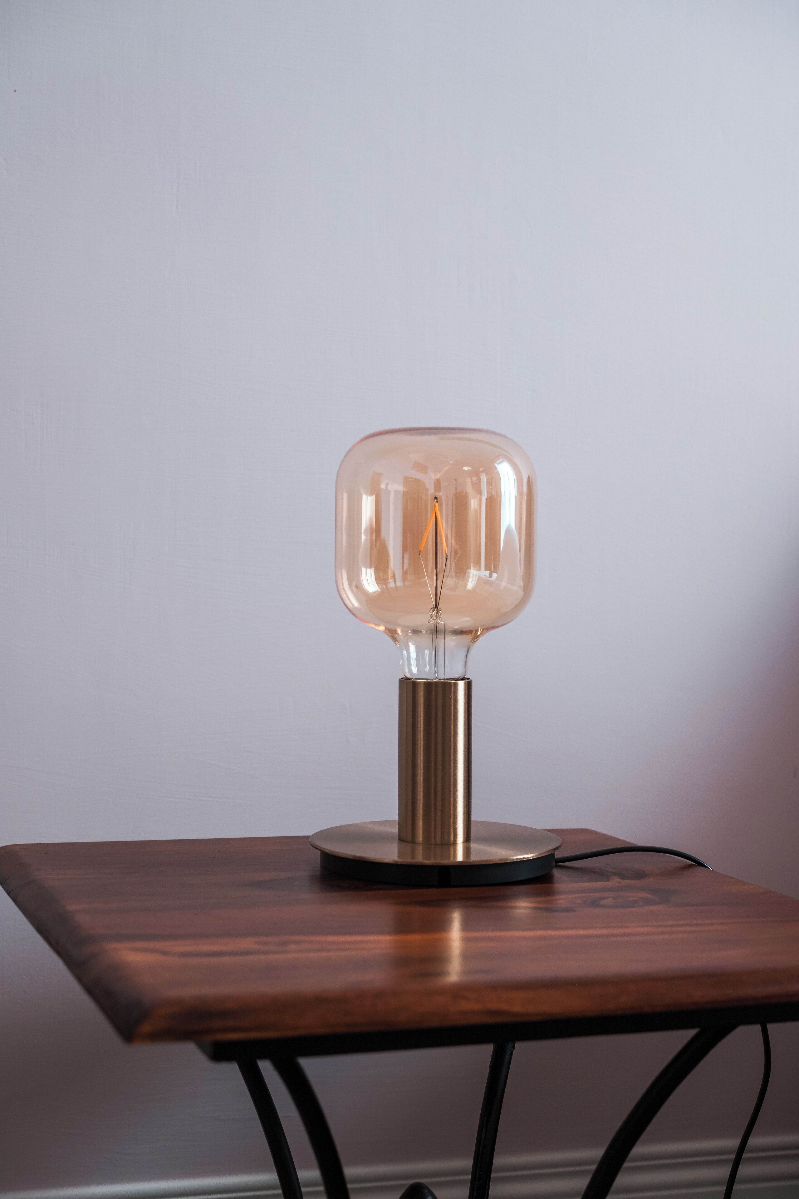 Ett bord med en lampa av klart glas ovanpå.