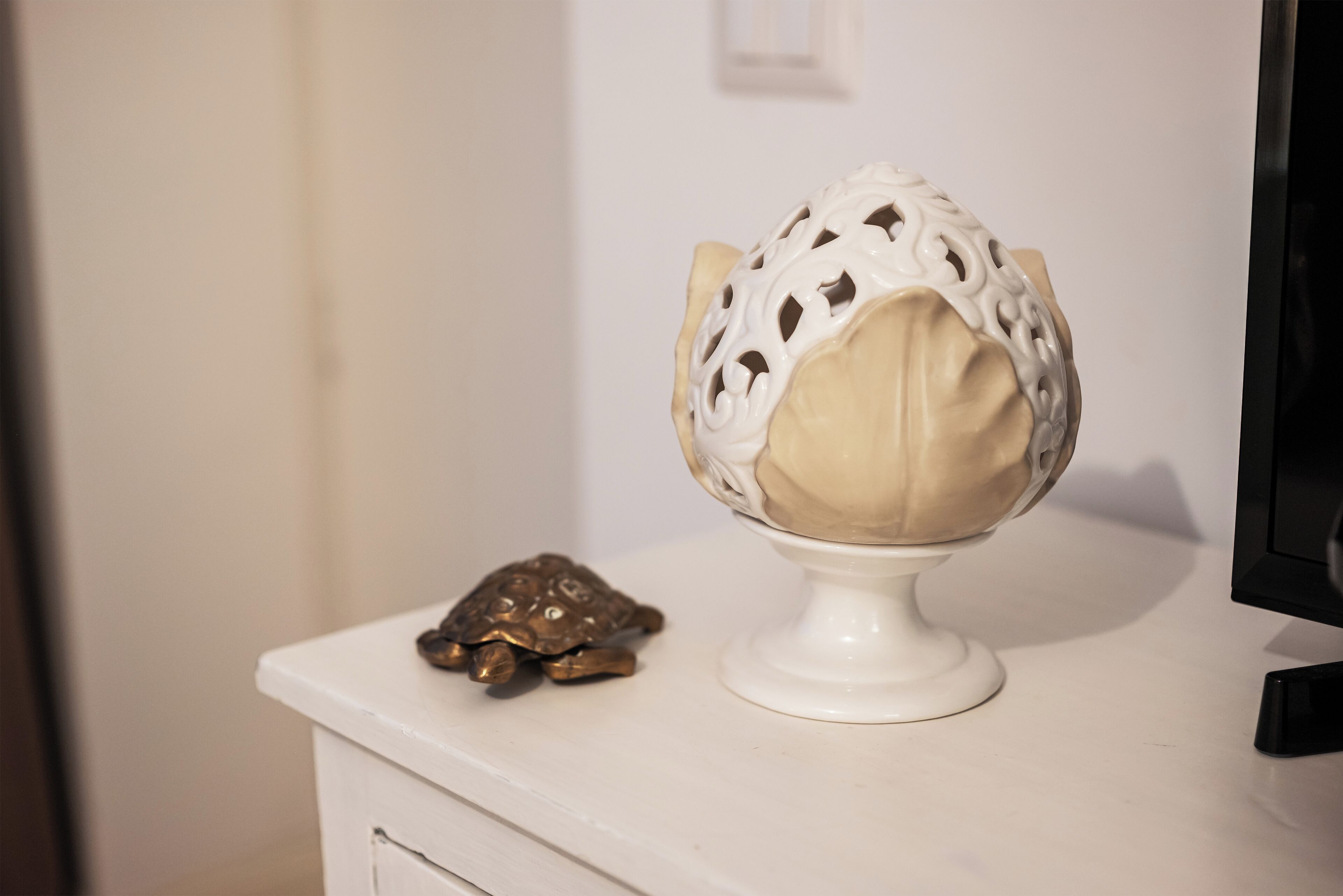 A white pedestal with a decorative object resembling a turtle and a spherical object with intricate patterns.