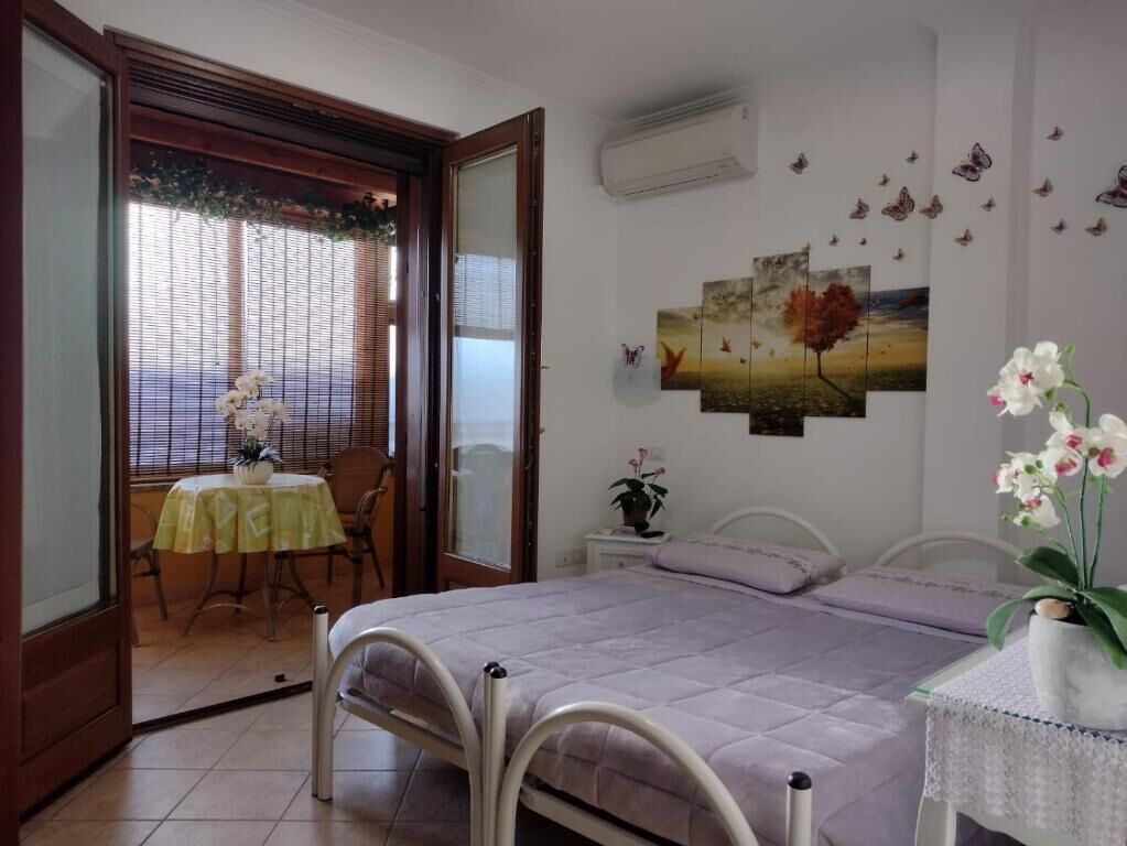 Un dormitorio con una cama, una mesita de noche, una silla, una ventana con persianas y una pared decorada con mariposas.