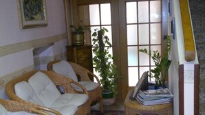 A living room with wicker furniture, a large window, and a staircase. - Hotel Centrale (Argenta)