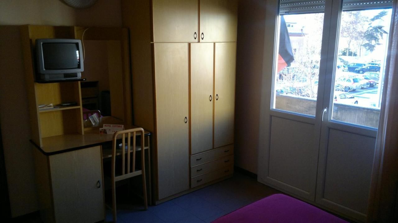 Ein Zimmer mit Schreibtisch, Stuhl, Kleiderschrank und Fernseher.