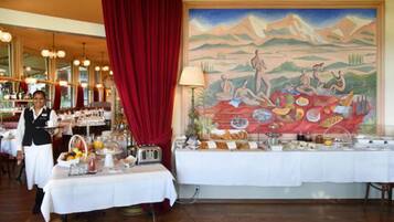 A restaurant with a buffet setup, a mural on the wall, and a red curtain.