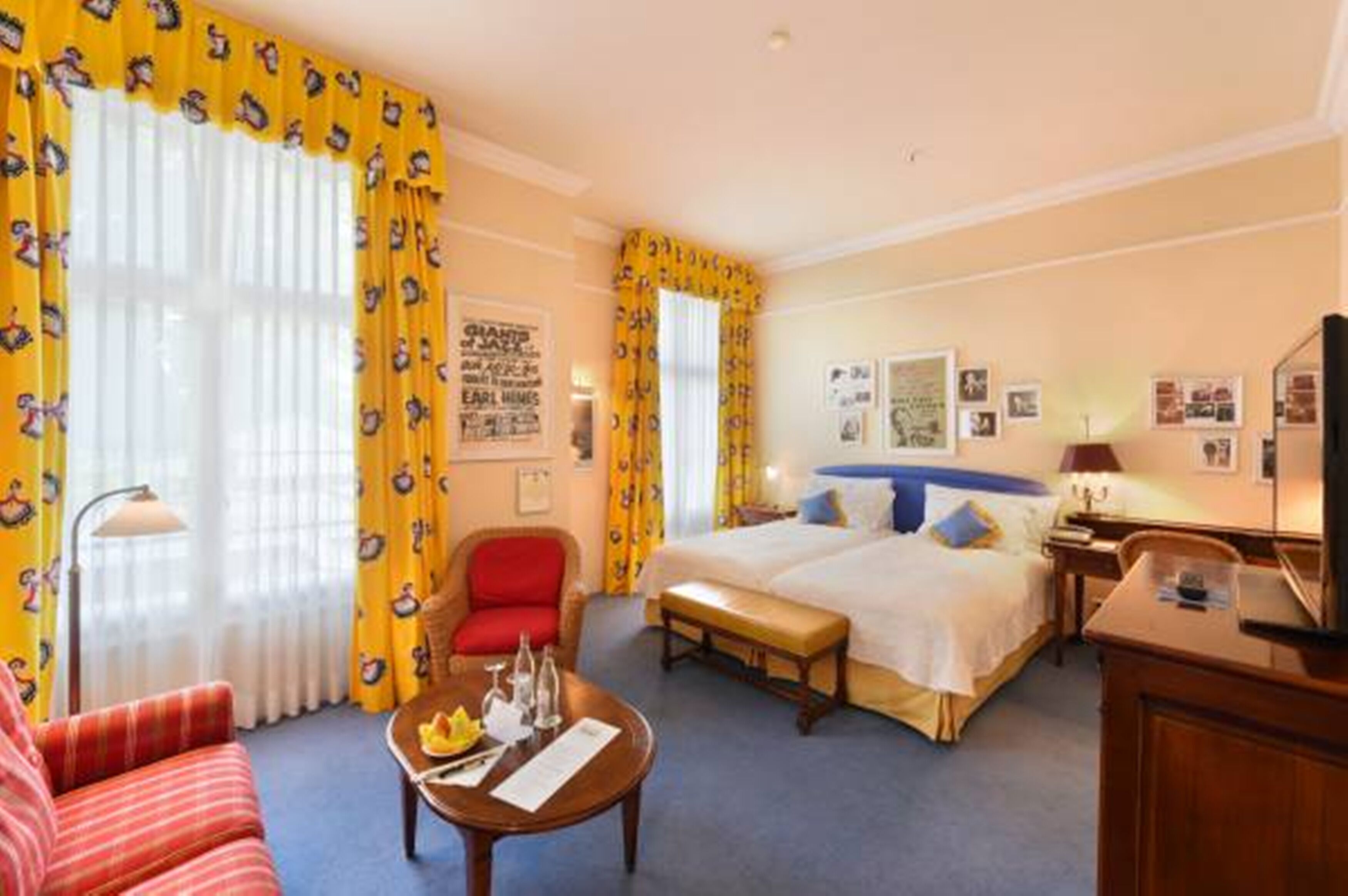 Una habitación de hotel con cama, escritorio, silla, mesa y ventana con cortinas.