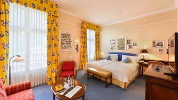 Una habitación de hotel con cama, escritorio, silla, mesa y ventana con cortinas.
