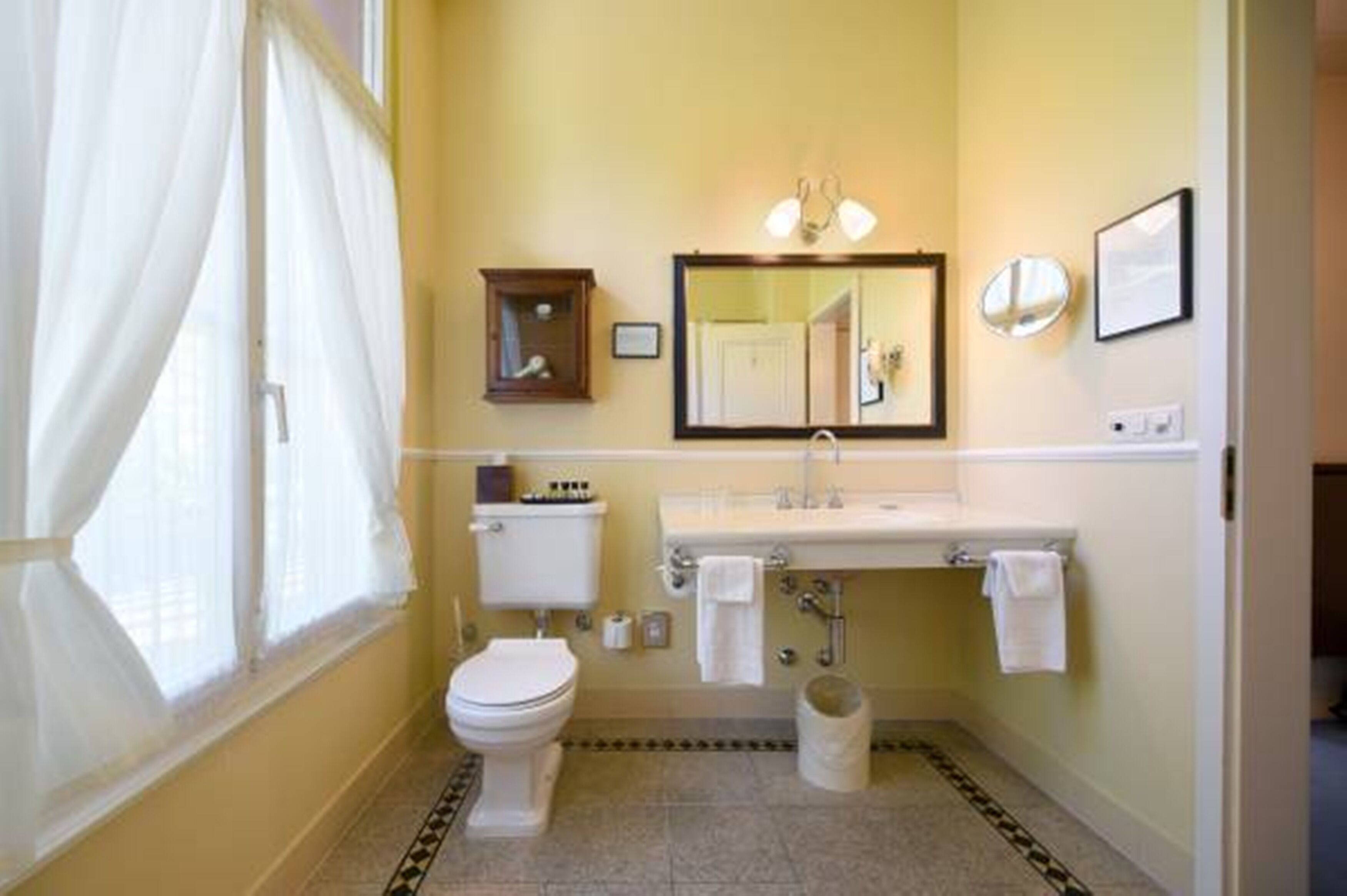Un bagno con WC, lavandino, specchio e un piccolo mobiletto.