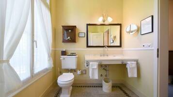 Un bagno con WC, lavandino, specchio e un piccolo mobiletto.