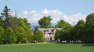 Ein großes Haus mit Garten und einem Feld im Vordergrund.